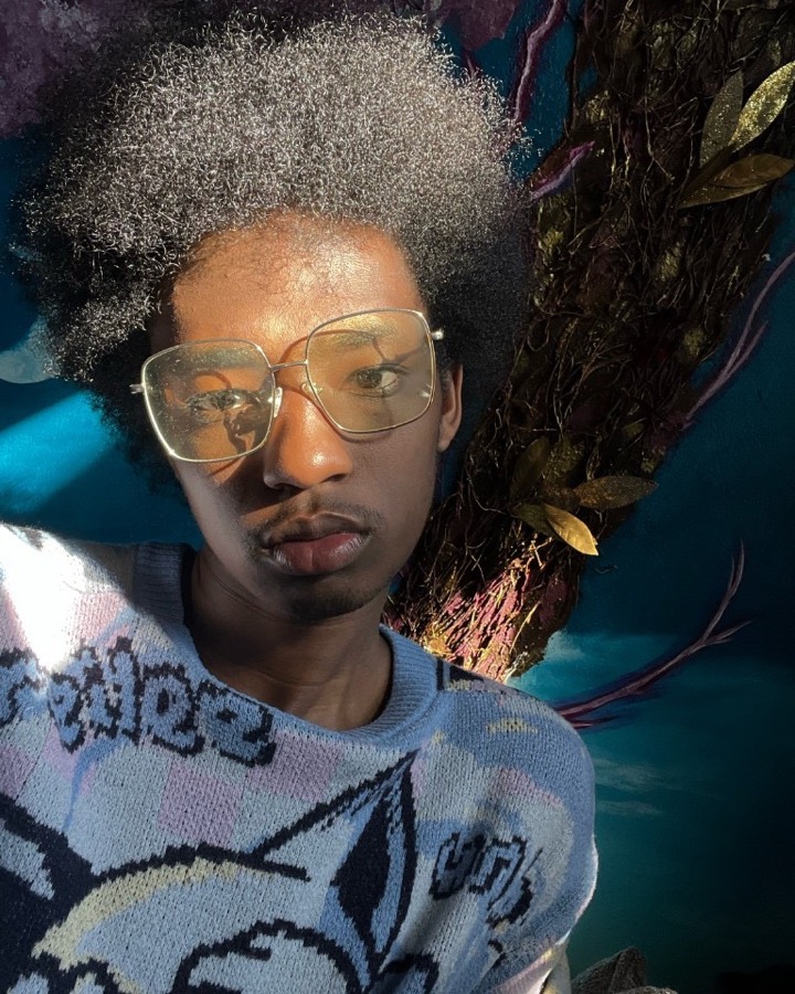 LaDonovan Walton, in glasses and a blue knit sweater, in warm sunlight